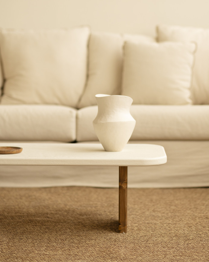 Couchtisch aus Mikrozement mit zwei dunkel gebeizten Holzbeinen, 95 cm lang.