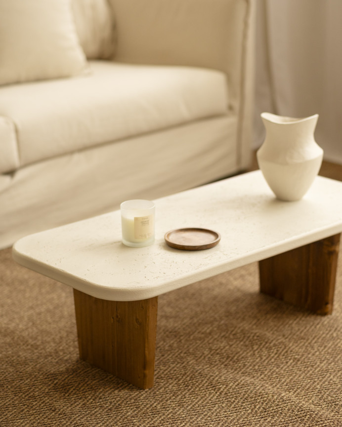 Couchtisch aus Mikrozement mit zwei dunkel gebeizten Holzbeinen, 95 cm lang.
