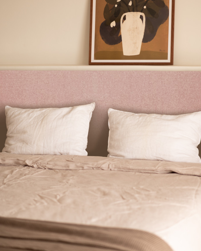 Upholstered headboard in plain polyester in pale pink color in various sizes.