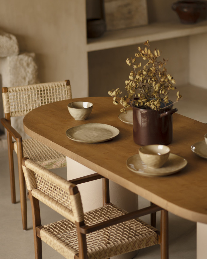 Oval dining table made of solid wood in a dark oak tone and micro cement legs in an earth tone, available in various sizes.