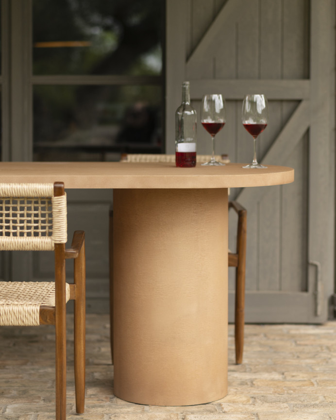 Oval dining table made of microcement in terracotta tone, available in various sizes.