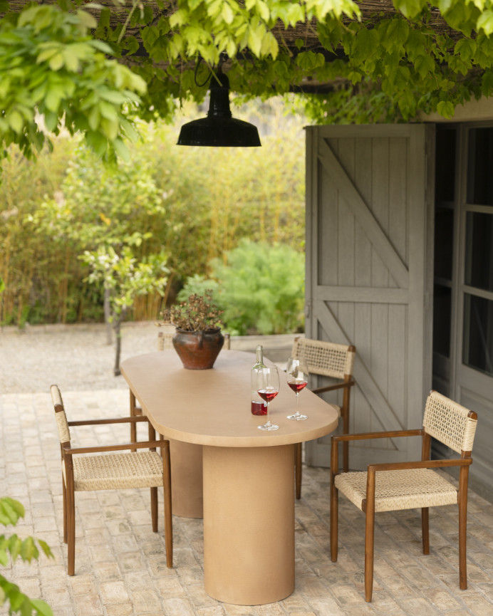 Oval dining table made of microcement in terracotta tone, available in various sizes.