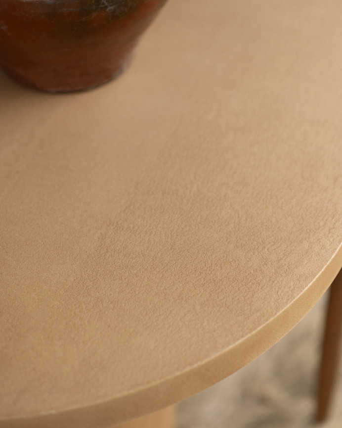 Oval dining table made of microcement in terracotta tone, available in various sizes.