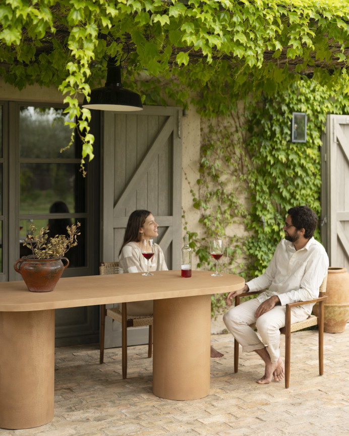 Oval dining table made of microcement in terracotta tone, available in various sizes.