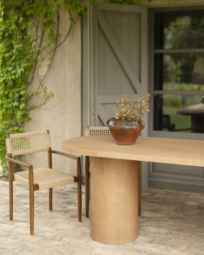 Oval dining table made of microcement in terracotta tone, available in various sizes.