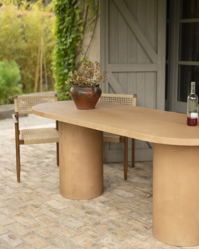Oval dining table made of microcement in terracotta tone, available in various sizes.