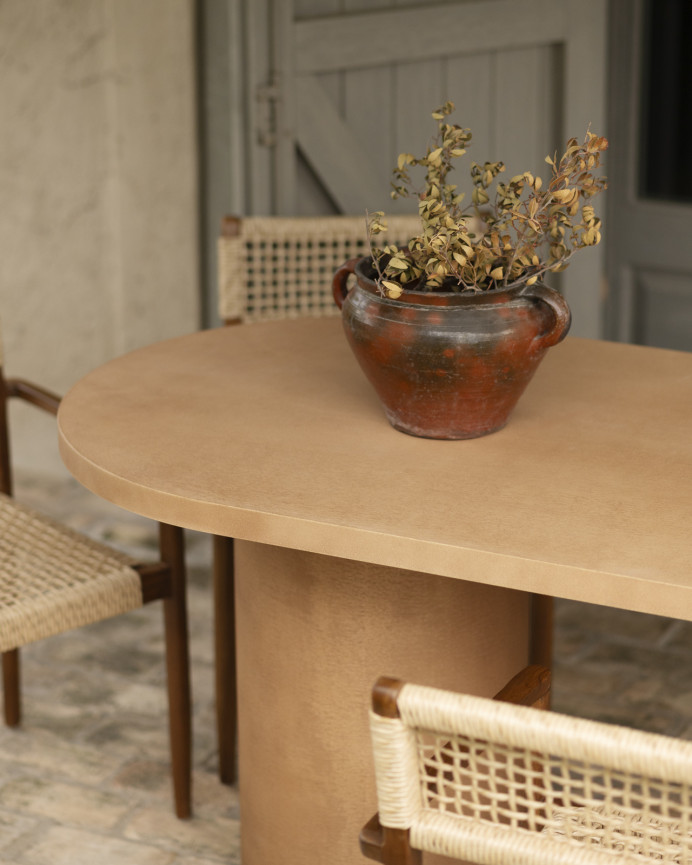 Oval dining table made of microcement in terracotta tone, available in various sizes.
