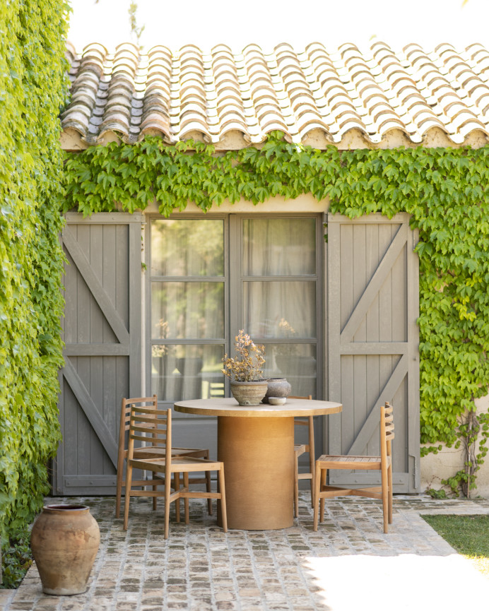 Round solid wood dining table in medium oak tone and terracotta microcement legs in various sizes.