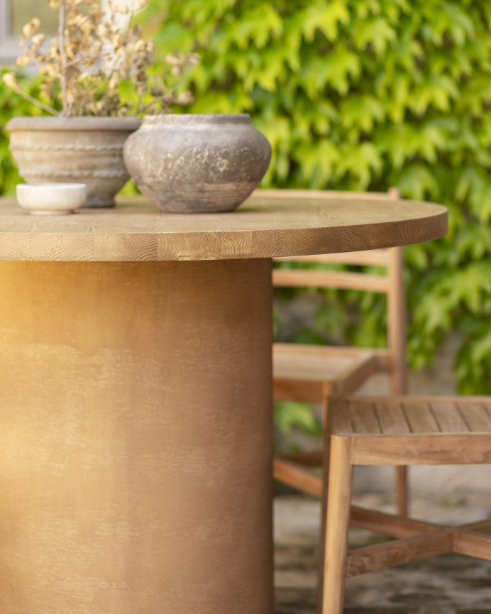 Round solid wood dining table in medium oak tone and terracotta microcement legs in various sizes.