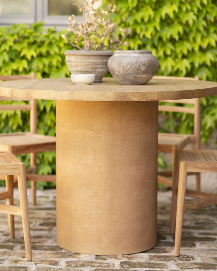 Round solid wood dining table in medium oak tone and terracotta microcement legs in various sizes.