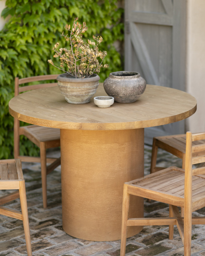 Round solid wood dining table in medium oak tone and terracotta microcement legs in various sizes.