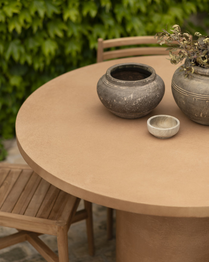Round dining table made of terracotta-tone microcement in various sizes.
