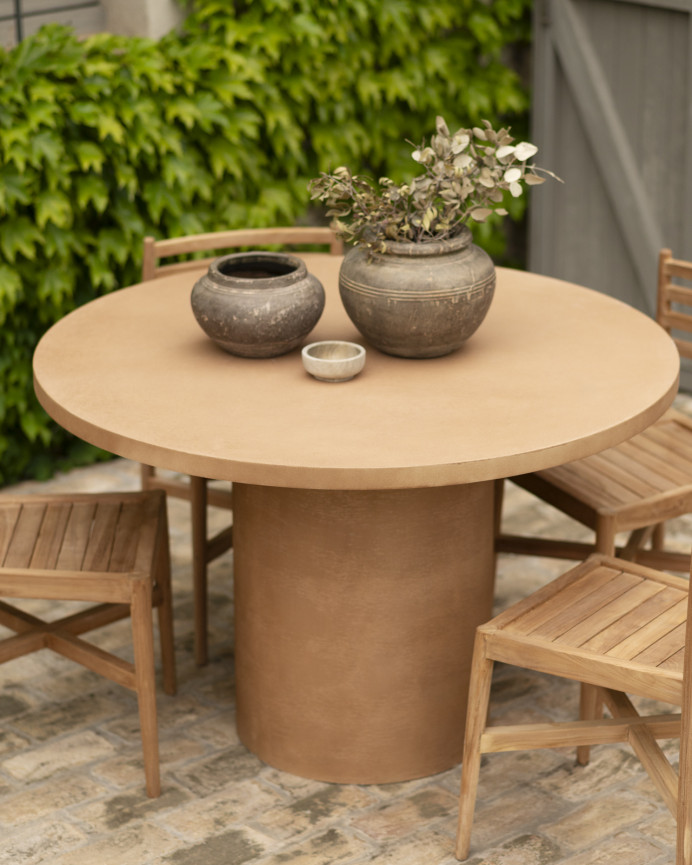 Round dining table made of terracotta-tone microcement in various sizes.