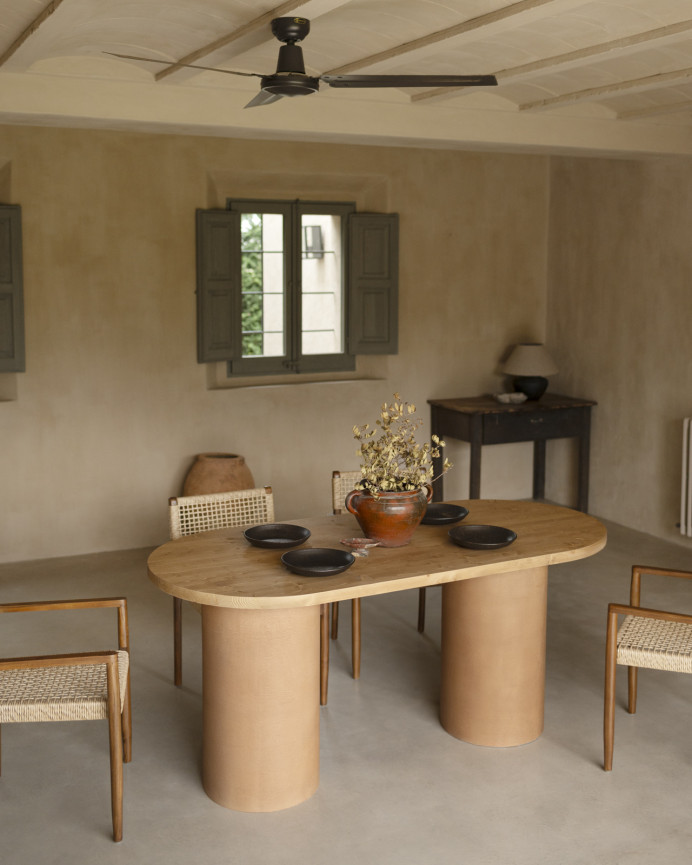 Oval solid wood dining table in medium oak tone with terracotta microcement legs in various sizes.