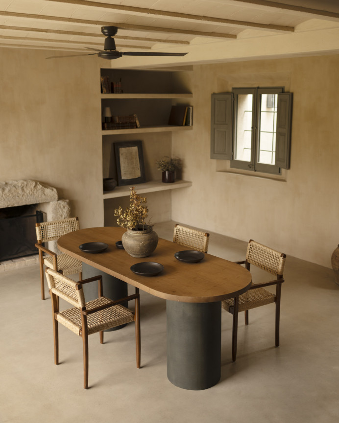 Oval solid wood dining table in dark oak tone with microcement legs in green tone, available in various sizes.