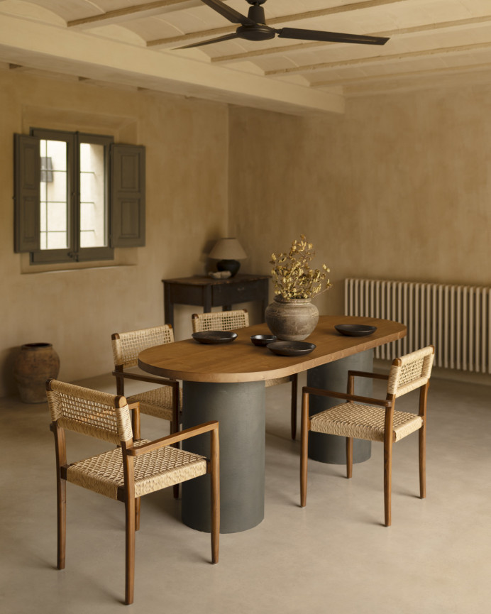 Oval solid wood dining table in dark oak tone with microcement legs in green tone, available in various sizes.