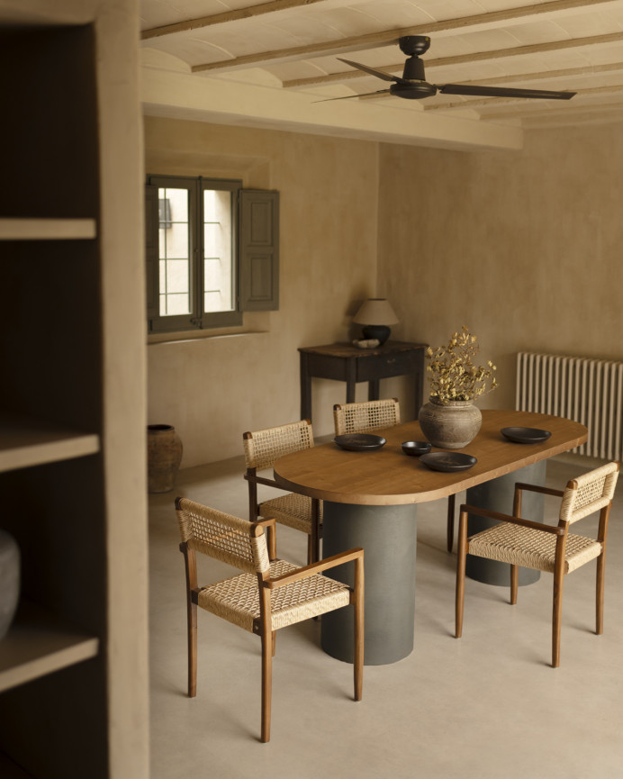Oval solid wood dining table in dark oak tone with microcement legs in green tone, available in various sizes.