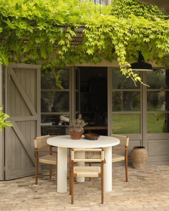 Round dining table made of microcement in off-white tone, available in various sizes.