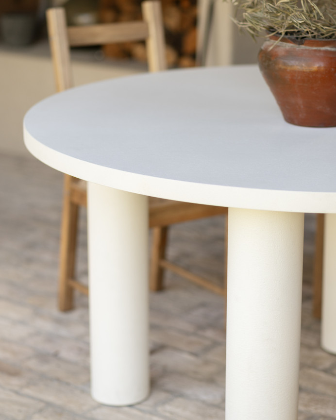 Round dining table made of microcement in a light off-white tone, available in various sizes.