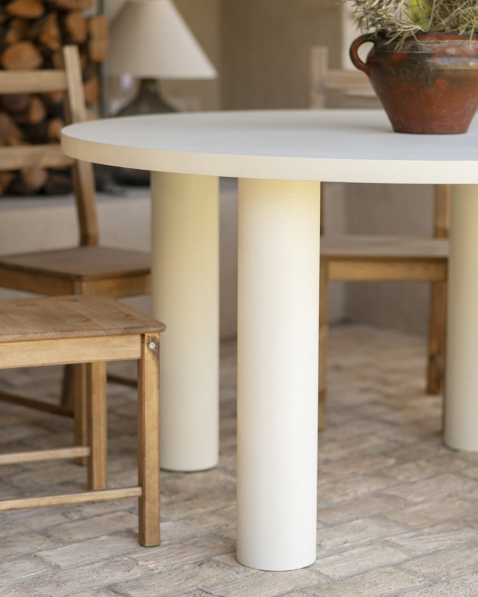 Round dining table made of microcement in a light off-white tone, available in various sizes.