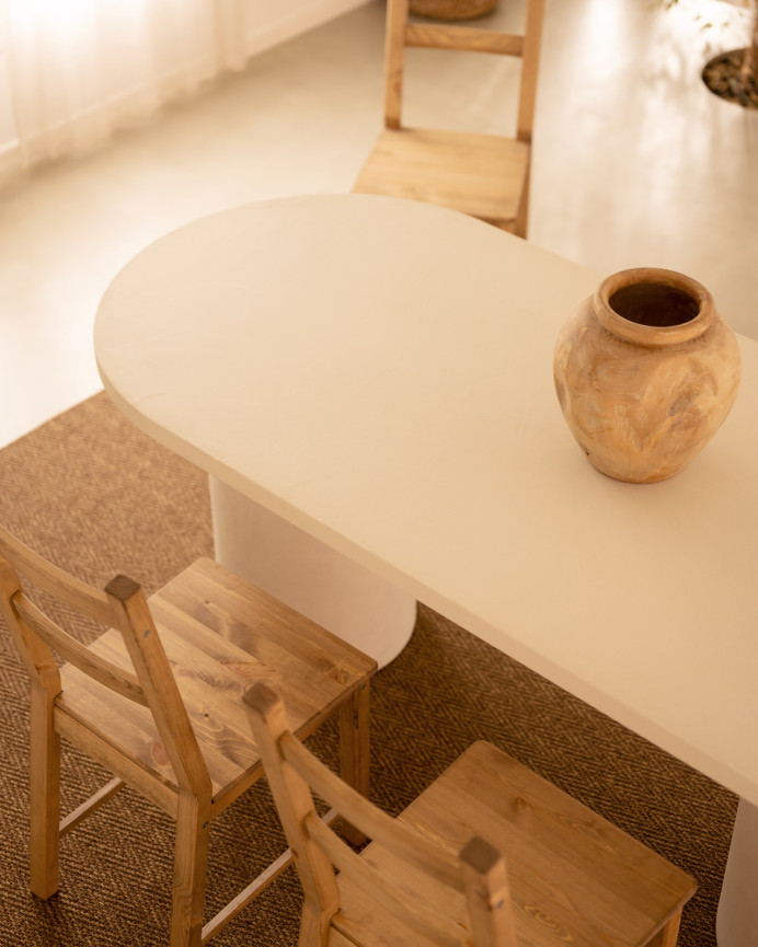 Oval dining table made of micro cement in a light off-white tone, available in various sizes.