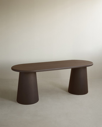 Oval dining table made of brown microcement in several sizes.