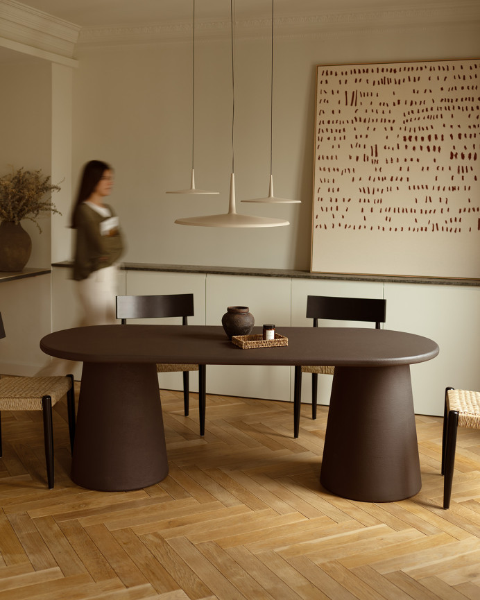 Oval dining table made of brown microcement in several sizes.