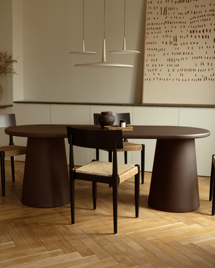 Oval dining table made of brown microcement in several sizes.