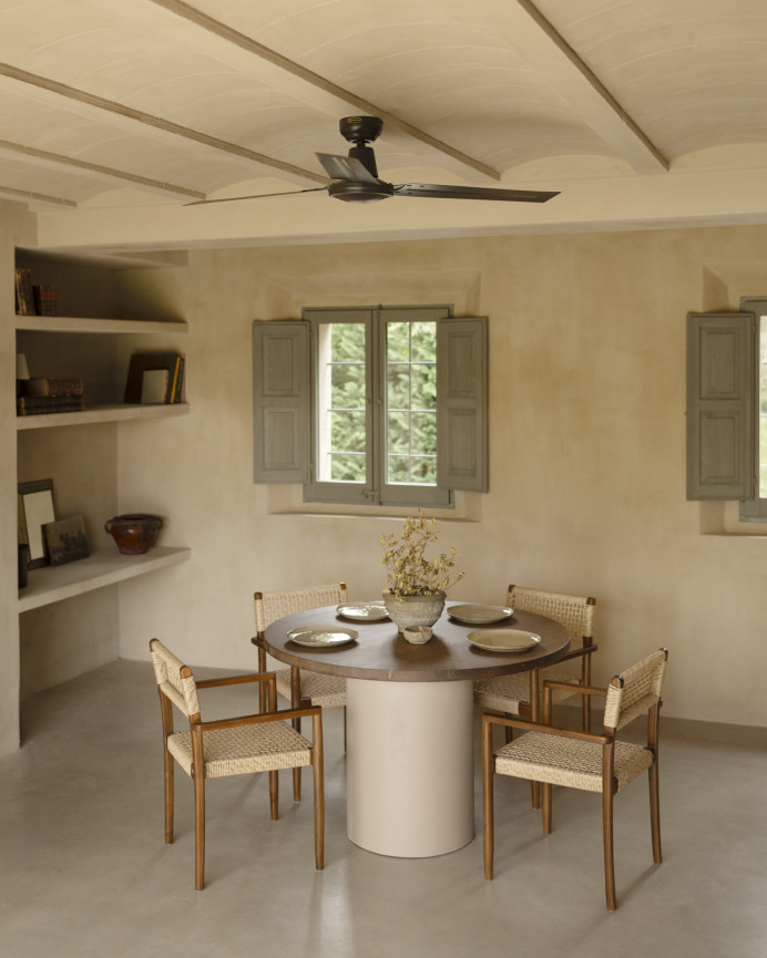 Round solid wood dining table in a dark oak tone with earth-tone micro-cement legs in various sizes.