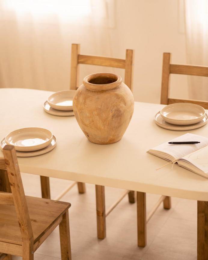 Oval dining table made of microcement in a light off-white tone with dark oak wood legs of various sizes.