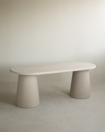 Oval dining table made of beige microcement in various sizes.