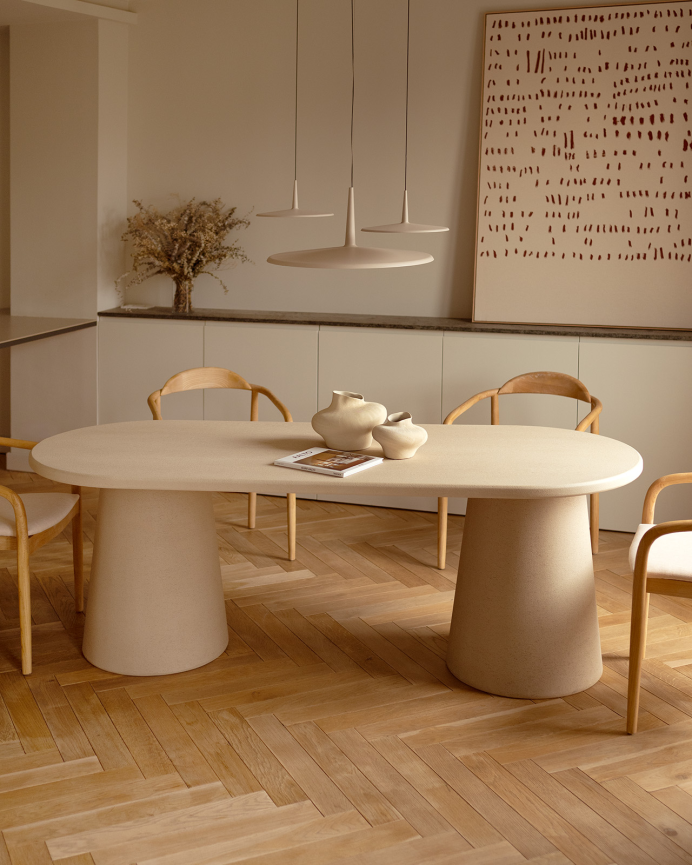 Oval dining table made of beige microcement in various sizes.