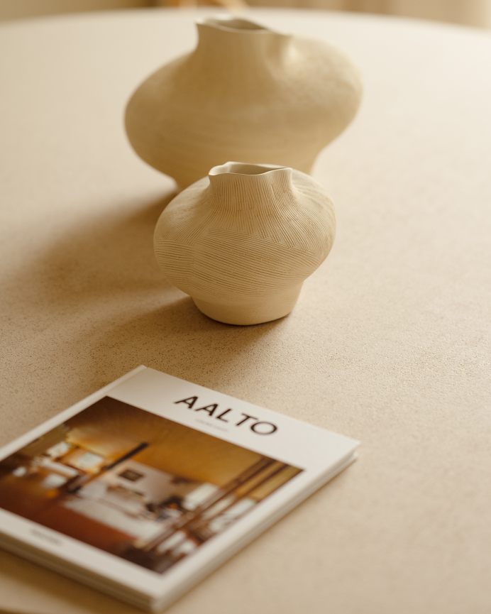 Round beige microcement dining table available in various sizes.