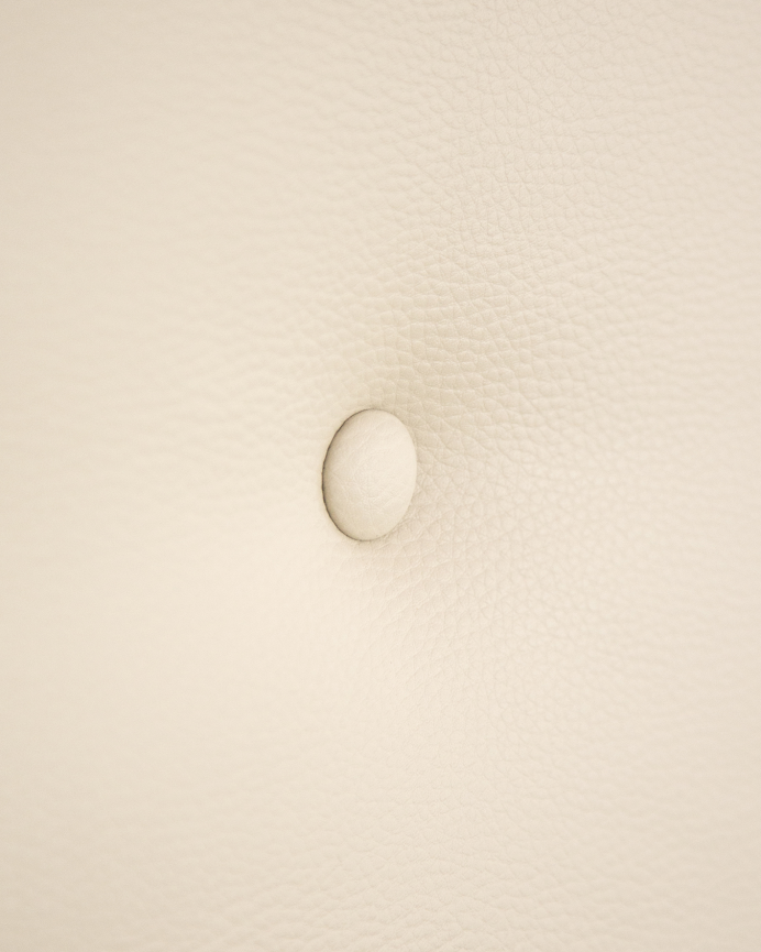 Upholstered headboard in faux leather with beige buttons in various sizes.