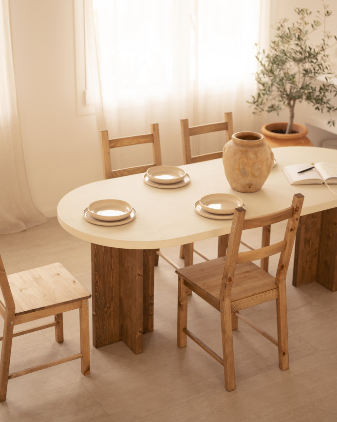 Mesa de comedor ovalada de microcemento en tono blanco roto con patas de madera tono roble oscuro de varias medidas