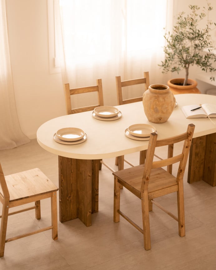 Mesa de comedor ovalada de microcemento en tono blanco roto con patas de madera tono roble oscuro de varias medidas