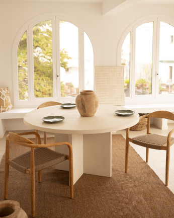 Table de salle à manger ronde en microciment de teinte blanc cassé disponible en plusieurs dimensions.