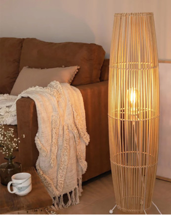 Lampadaire composé d'une base en métal blanc et de branches de bambou reliées par une tresse de fibres naturels.