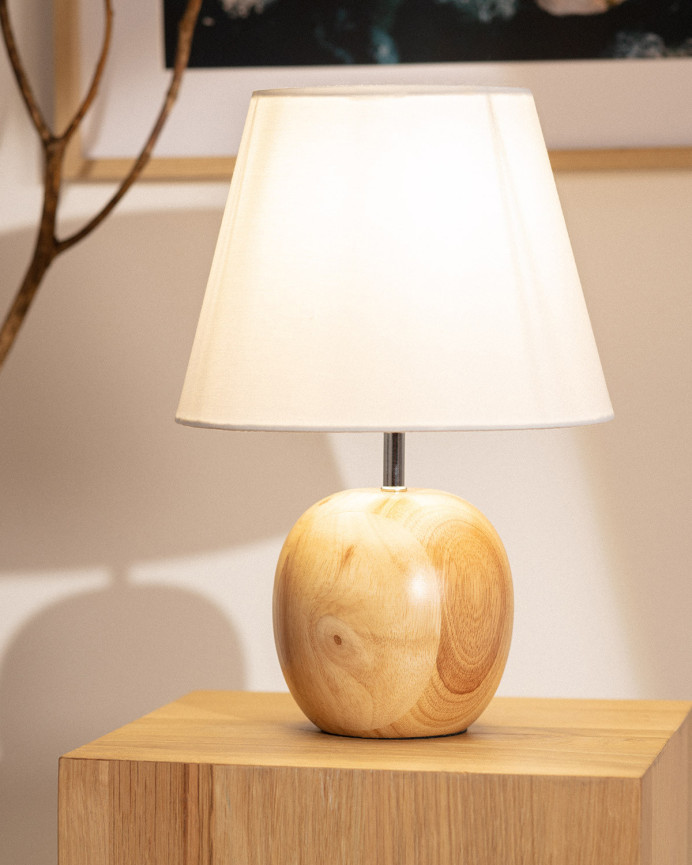 Lampada da tavolo realizzata con base in legno e paralume in tessuto di colore bianco.