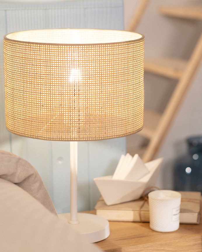 Lampada da tavolo realizzata con base metallica di colore bianco e paralume in rattan.