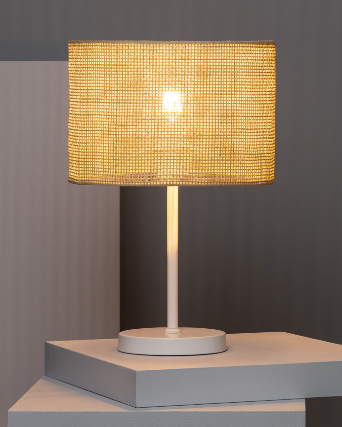 Lampada da tavolo realizzata con base metallica di colore bianco e paralume in rattan.