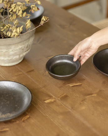 Tavolo da pranzo in legno massello in tonalità di rovere scuro e gambe in microcemento in tonalità verde di varie dimensioni.