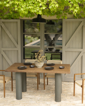 Tavolo da pranzo in legno massello in tonalità di rovere scuro e gambe in microcemento in tonalità verde di varie dimensioni.