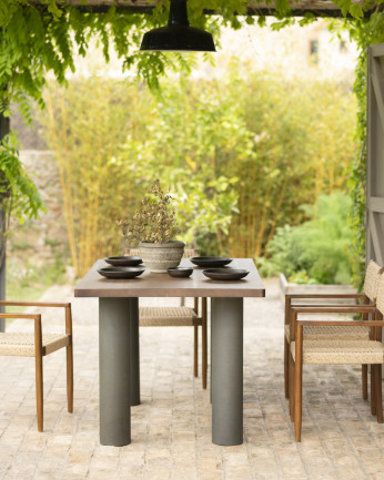 Tavolo da pranzo in legno massello in tonalità di rovere scuro e gambe in microcemento in tonalità verde di varie dimensioni.